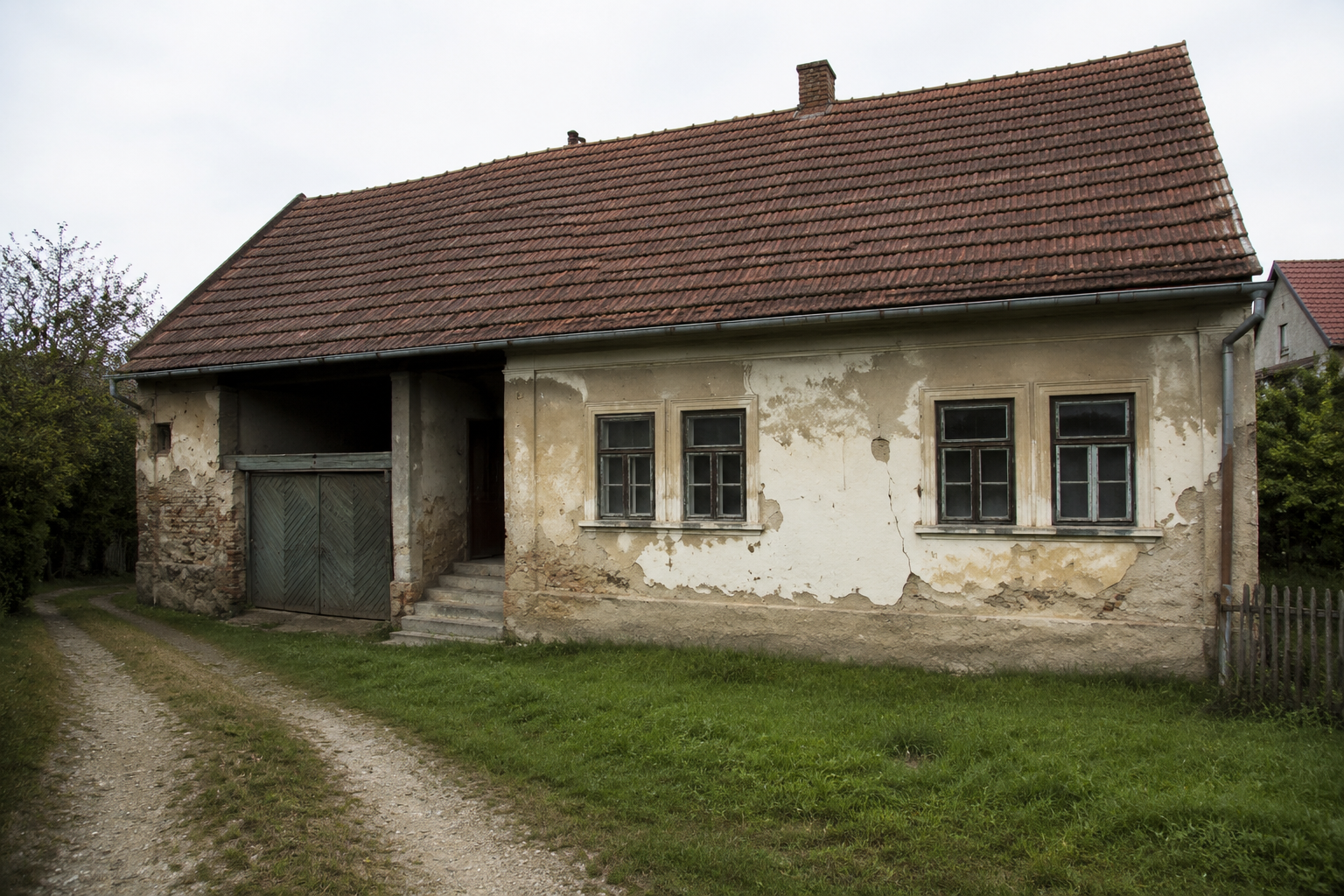 Starší rodinný dům s bílou fasádou a oranžovou střechou vhodný pro renovaci v rámci NZÚ