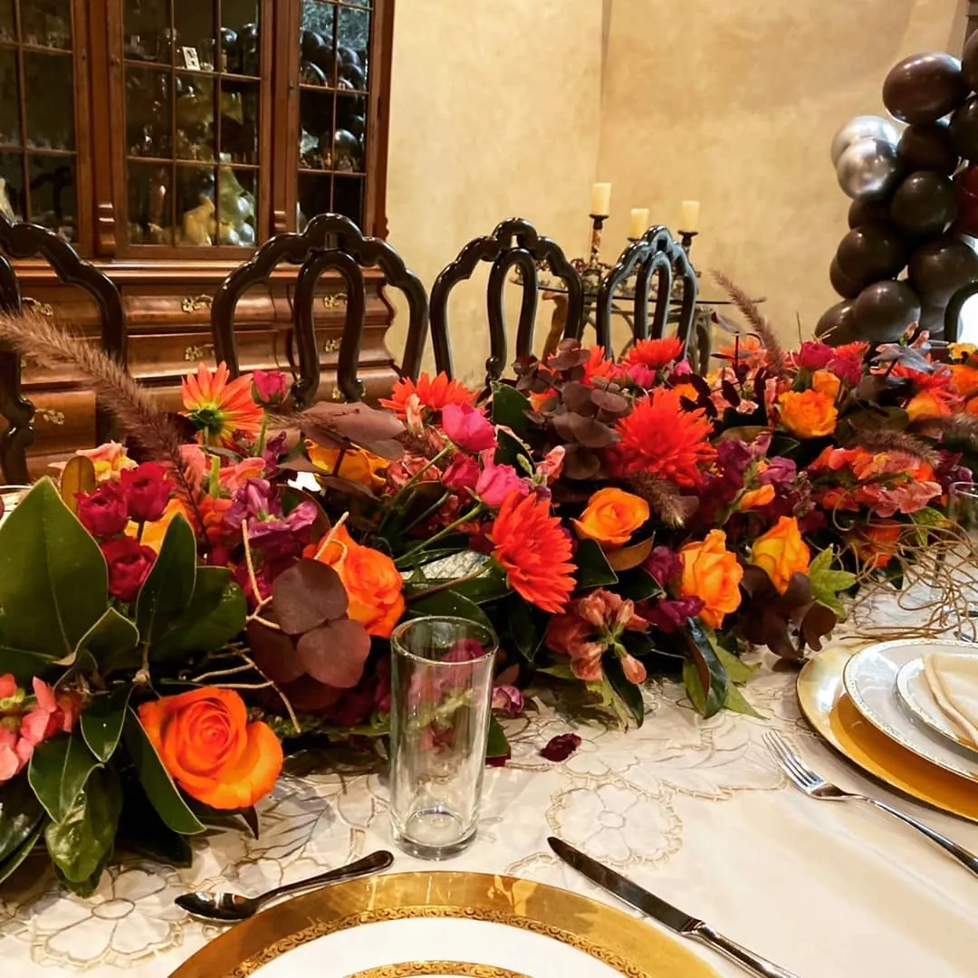 Centro de mesa de otoño en naranja y rojo con vajilla dorada