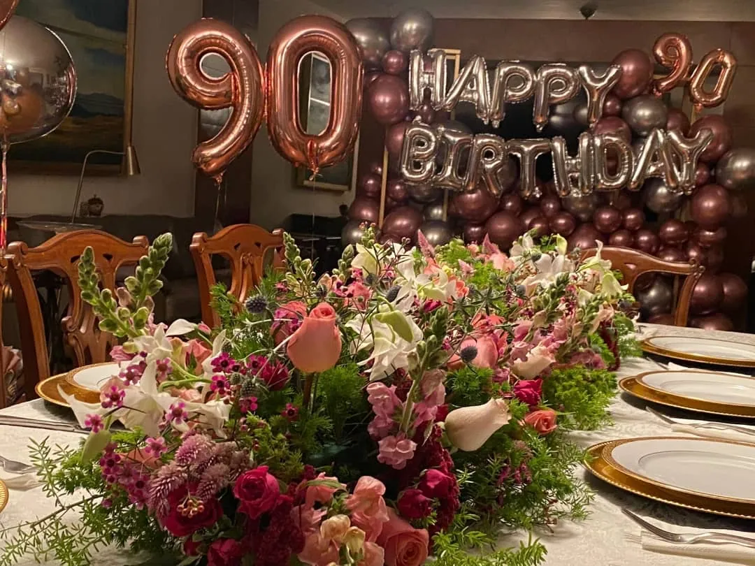 Mesa con flores rosas para un cumpleaños de 90 años