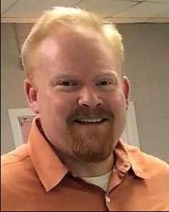 Mike Fielding smiling in an orange button-down shirt