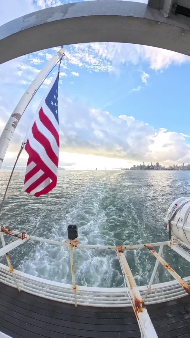 An American flag on the back deck of the Alcatraz ferry with the San Francisco skyline across the bay