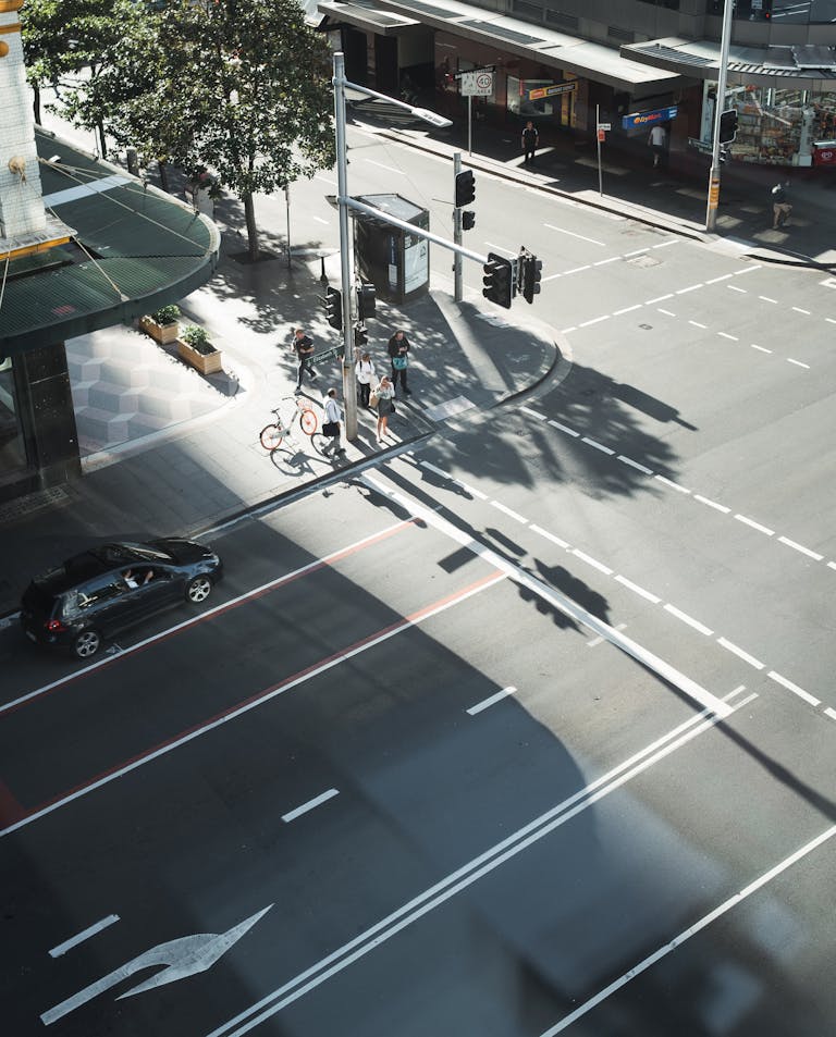 A bustling city intersection in Sydney with pedestrians and traffic captured from above on a sunny day.