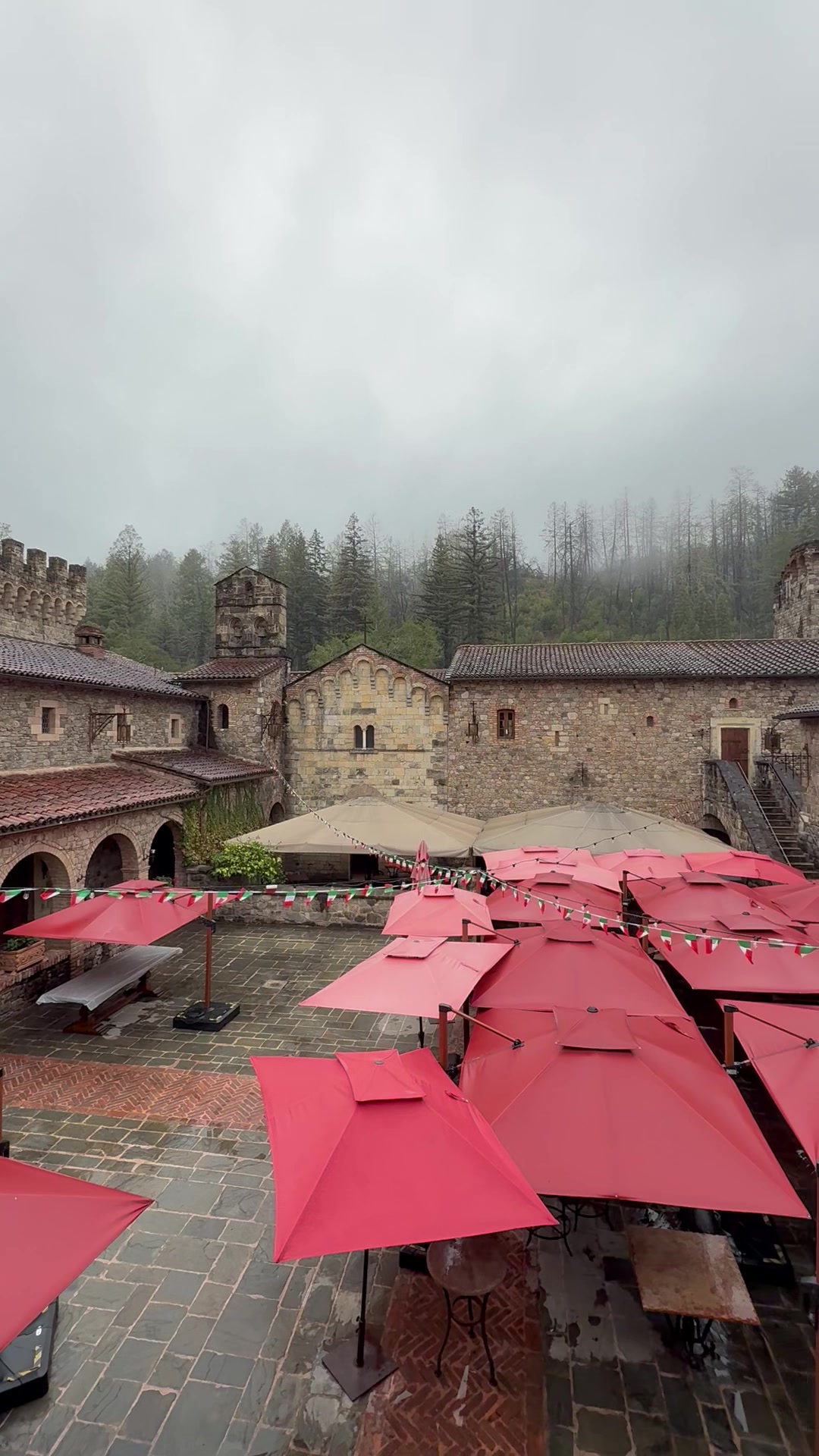 The castle courtyard at Castello di Amorosa with red umbrellas set up for wine tastings