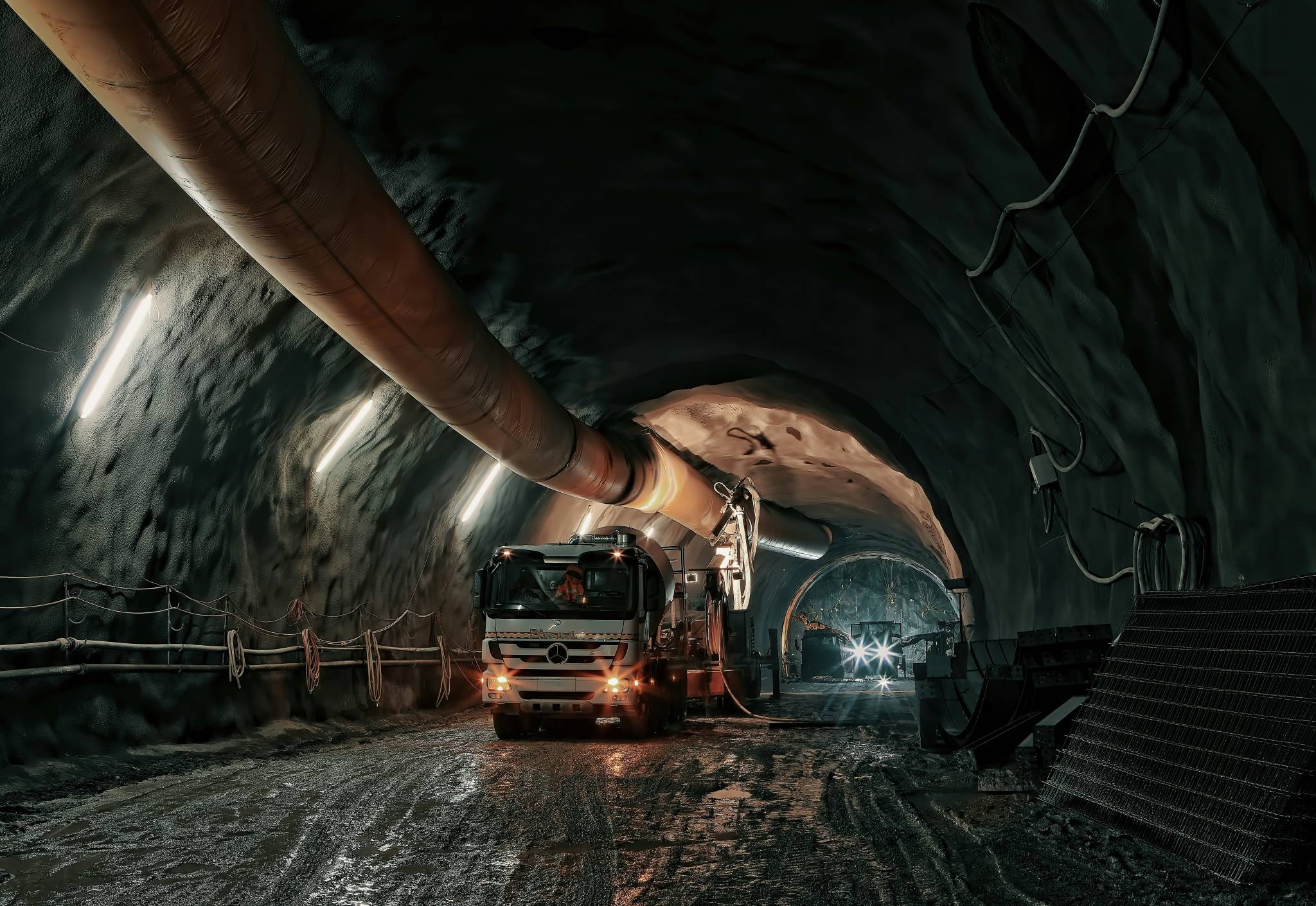 A truck operates in an underground mining tunnel with ventilation systems, representing the challenging environment of FIFO mining jobs no experience required. These entry-level positions offer opportunities for individuals new to the mining industry.
