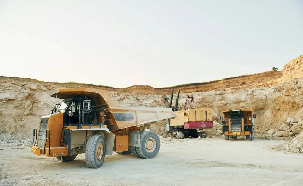 Large industrial trucks and machinery at a quarry or mining site, showcasing equipment used in FIFO jobs for workers on a working holiday in remote areas.