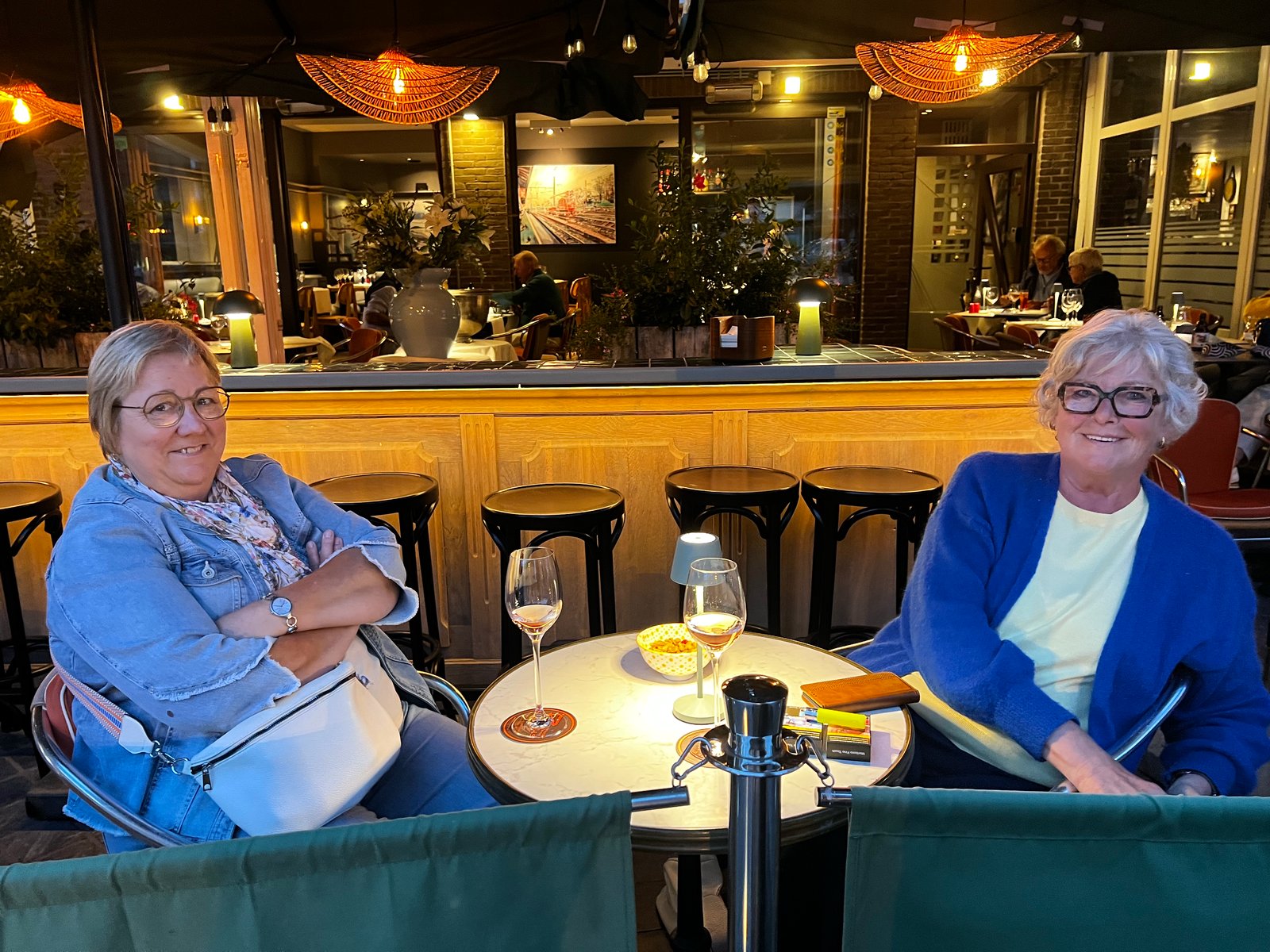 Gasten in gesprek aan de bar onder de parasols