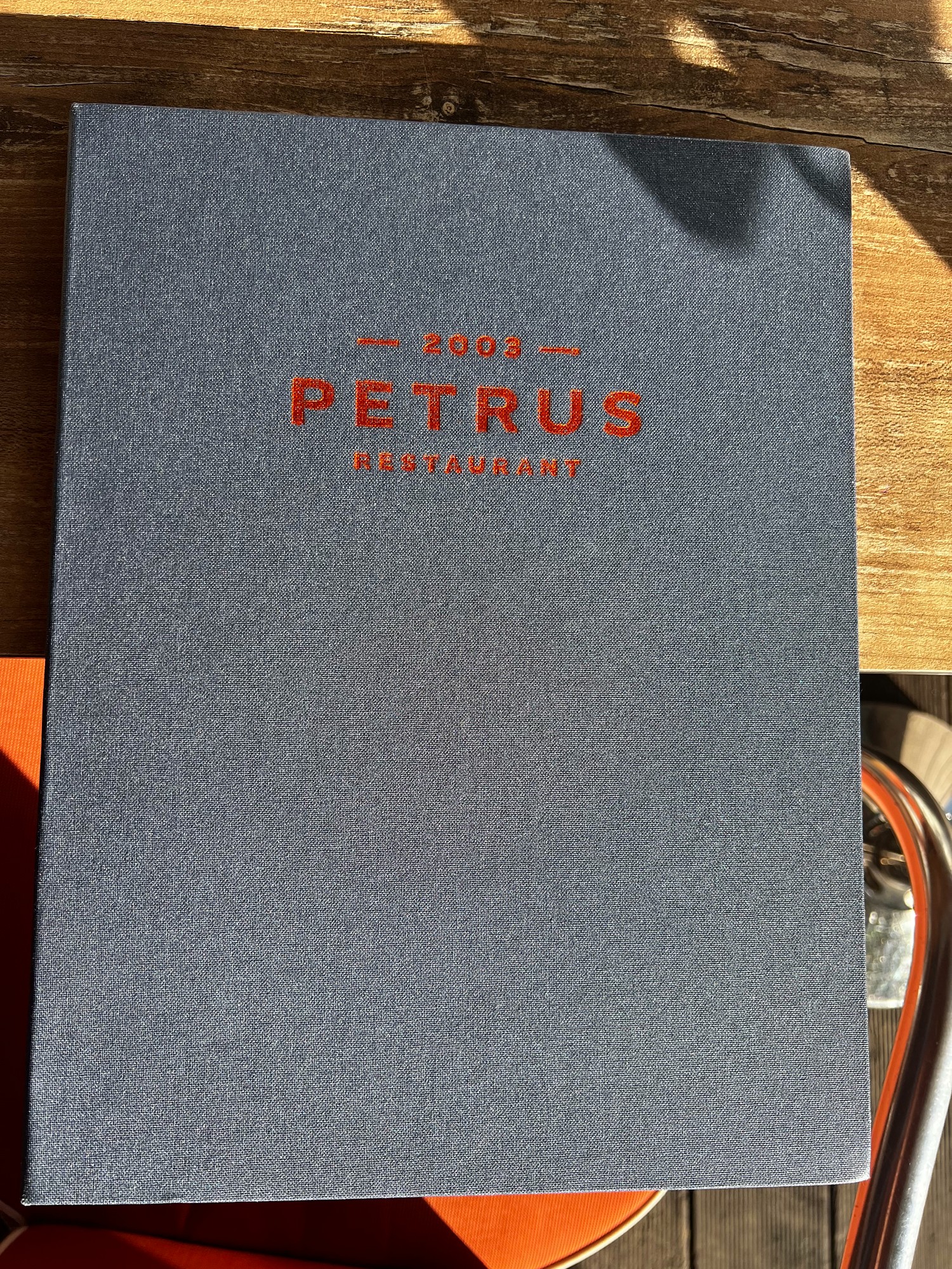Menukaart van Petrus op een houten tafel in de zon