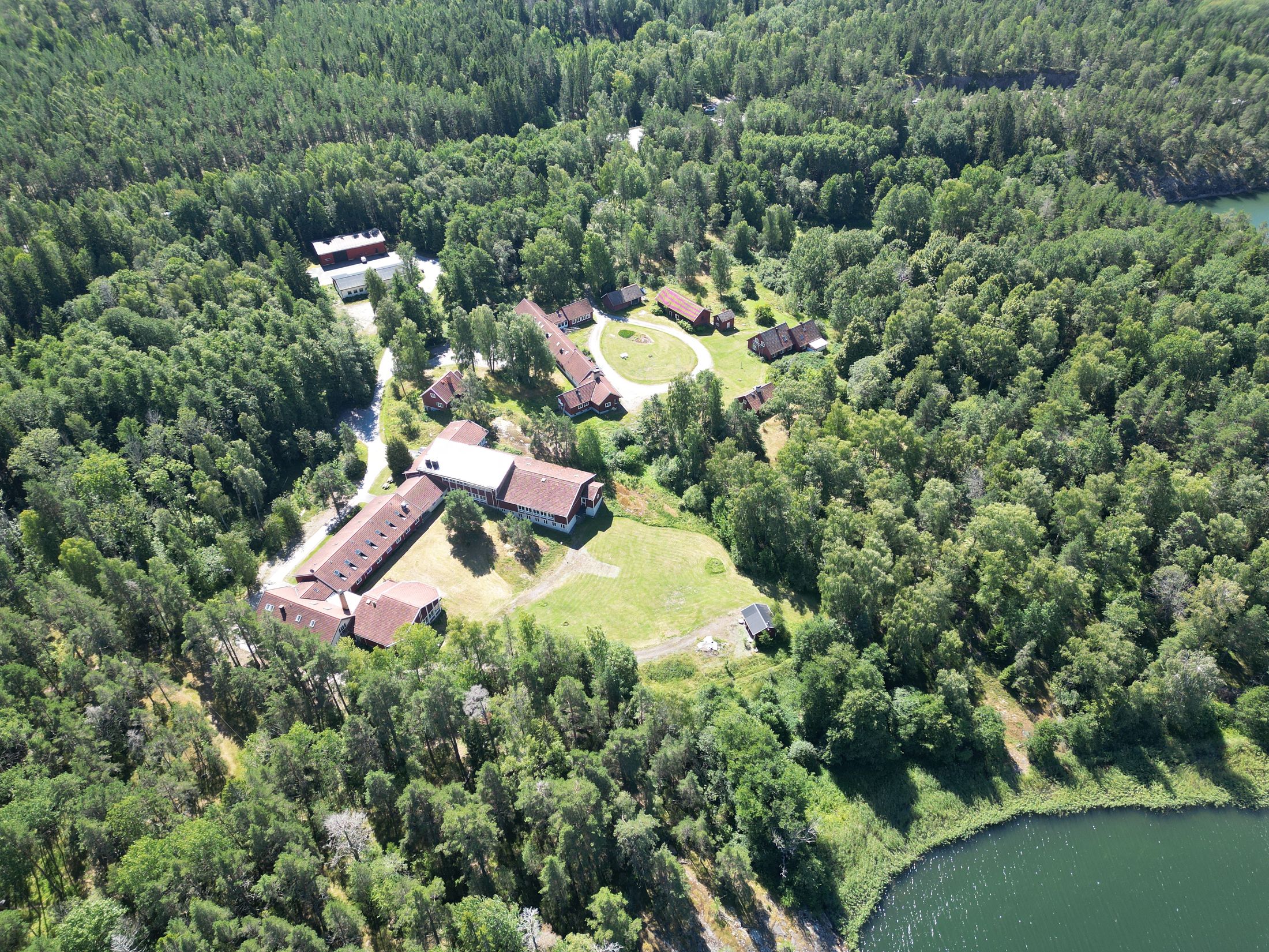 Ladvik sett från luften: röda trähus i skogen vid vattnet utanför Vaxholm