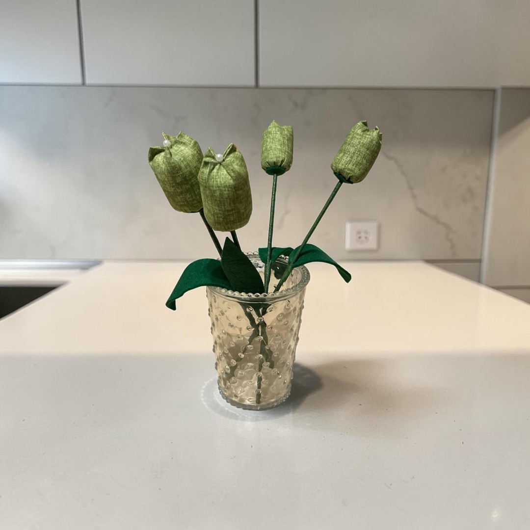 Close-up of a dark green mottled fabric tulip bloom with green felt leaf and pearl detail