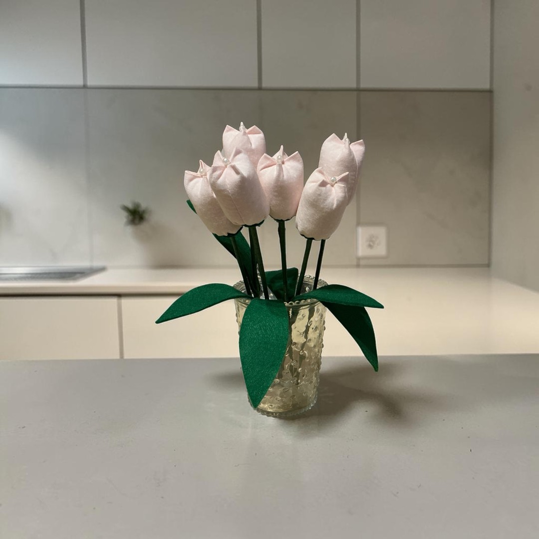 Close-up of pale pink spotted fabric tulip bloom with green felt leaf and pearl details