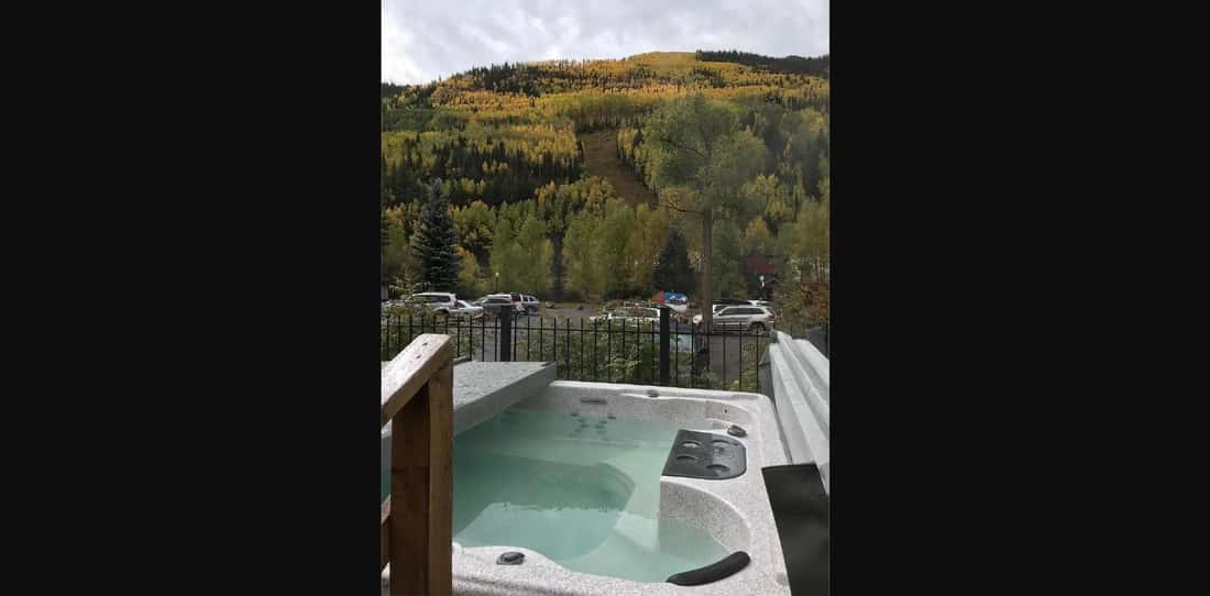 Outdoor hot tub at Telluride Lodge with a forested hillside beyond.