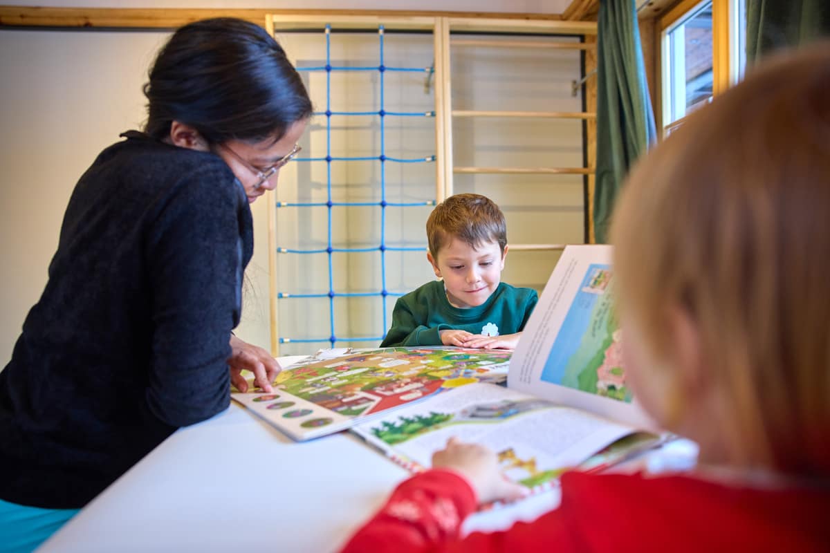 Kinder und Erwachsene lesen am Tisch vor dem Kletternetz