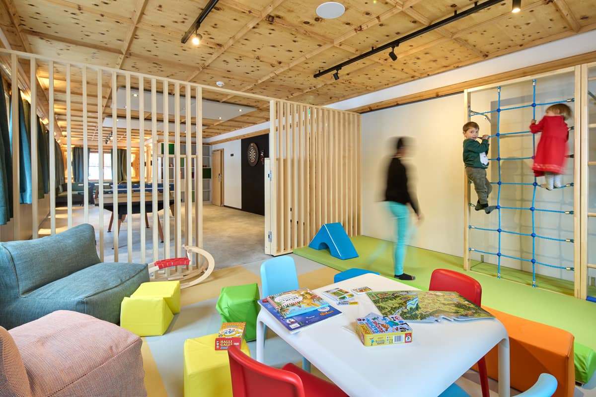 Sitzecke mit grüner Bank, Holzstühlen und Spiele-Regal im Kidsroom