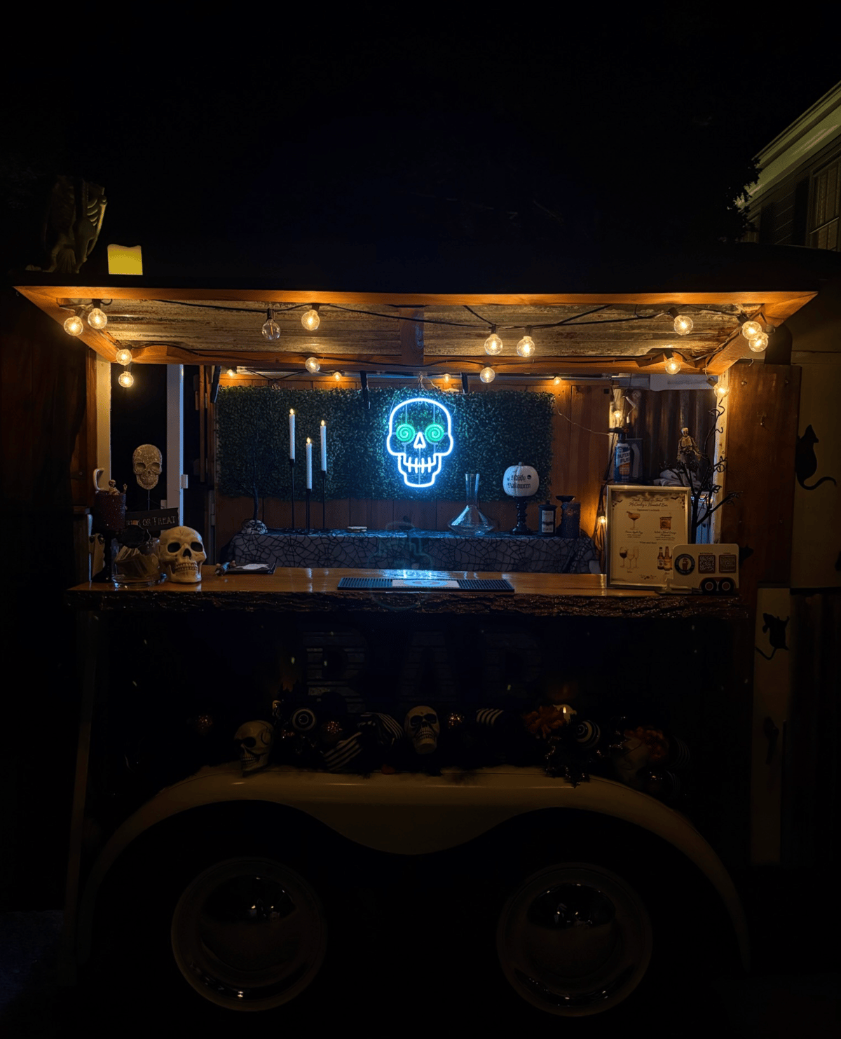 The Hitching Post Halloween bar at night with a glowing skull neon sign and spooky decor