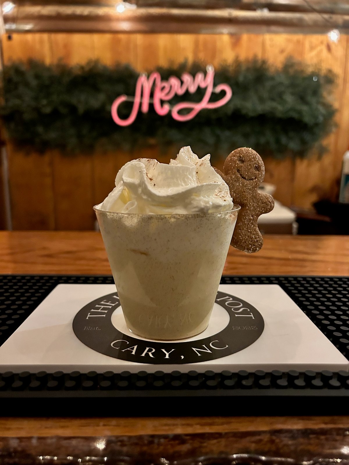 Hot cocoa topped with whipped cream and a gingerbread man at a Hitching Post holiday cocoa bar