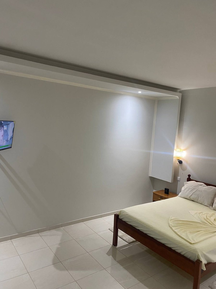Suite bedroom with double bed, television and glossy tiled floor at Residencial Bigasso