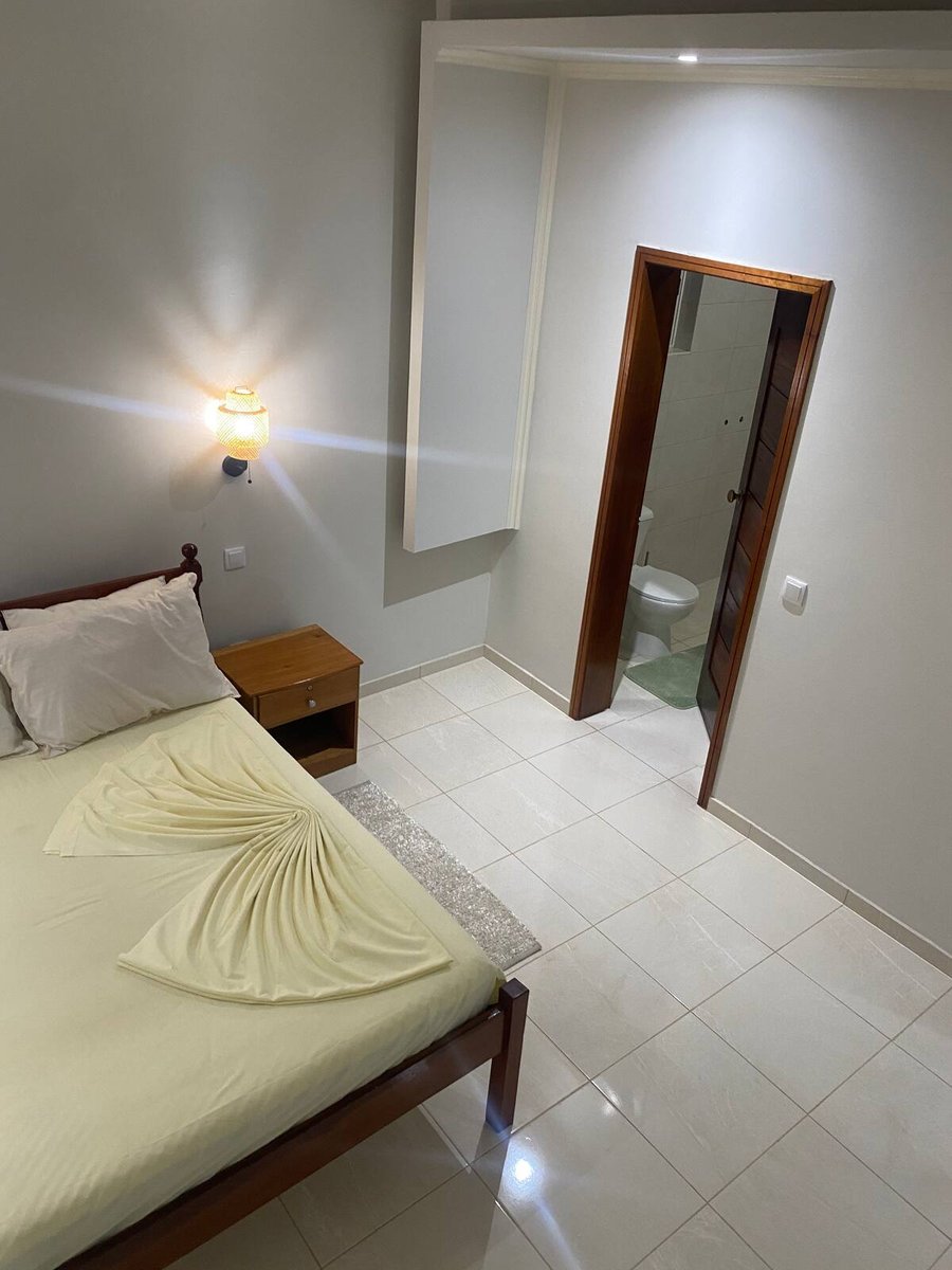 Suite bedroom with tiled floor and open en-suite bathroom door at Residencial Bigasso