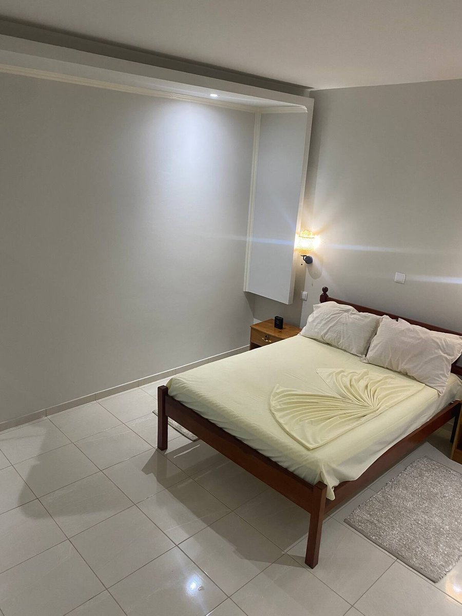 Guest bedroom with wall lamp, wardrobe and double bed at Residencial Bigasso