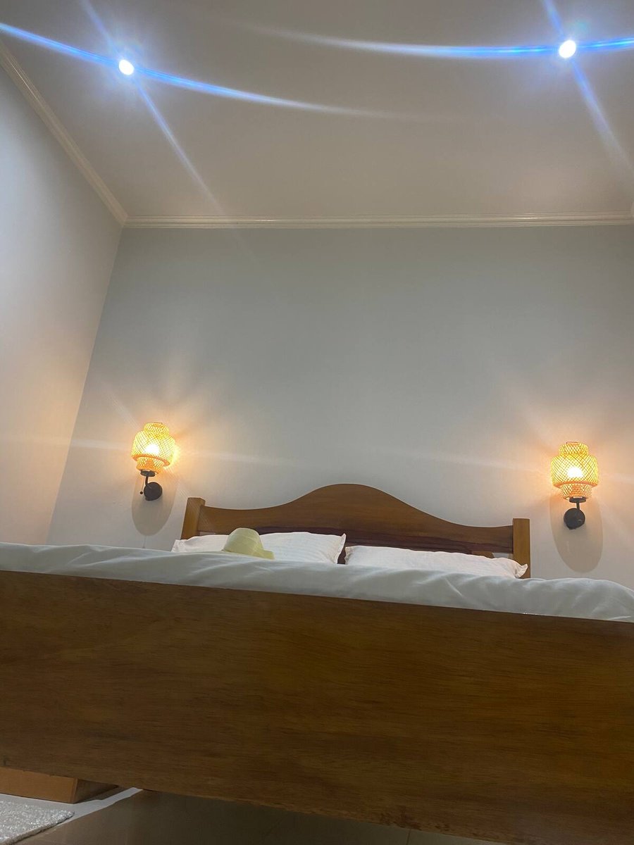 Carved wooden double bed with crisp white bedding at Residencial Bigasso