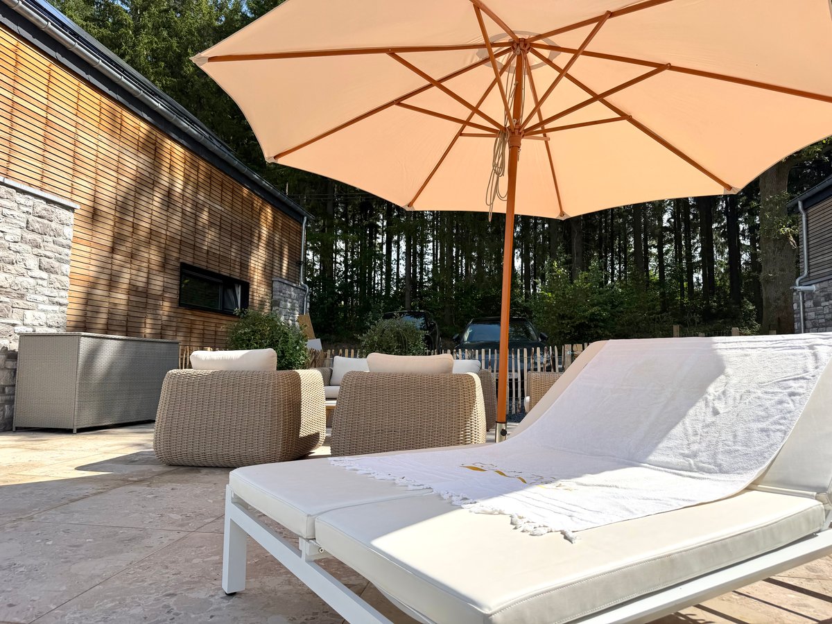 Zonneterras met houten eettafel, omheinde tuin en uitzicht over de heuvels