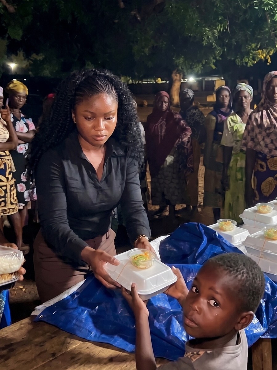 TWHM Foundation volunteer handing a hot meal to a young boy in Accra, Ghana