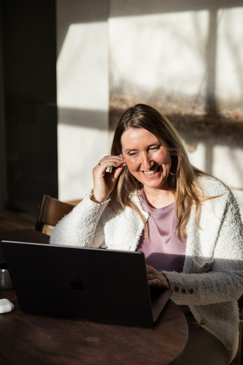 Heidi Segers, zaakvoerder van Tikaani Growth, achter haar laptop in een warm verlichte koffiebar