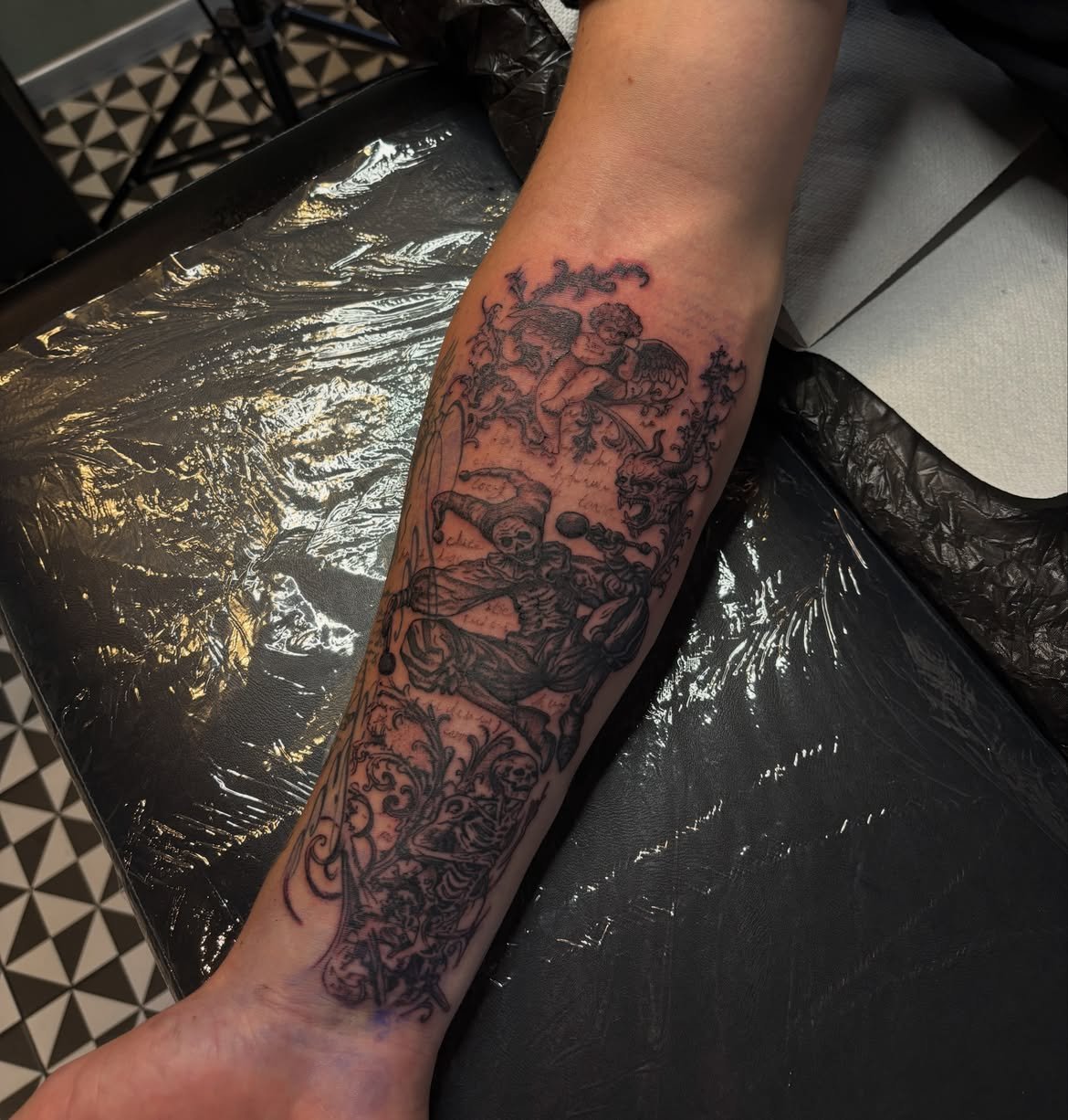 Ilustratívne black & grey tetovanie kostlivca a anjelika na predlaktí, Arthur Tatts