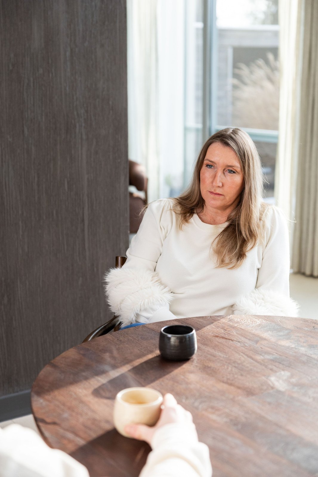 Heidi Segers luistert aandachtig tijdens een coachingsgesprek aan een houten tafel