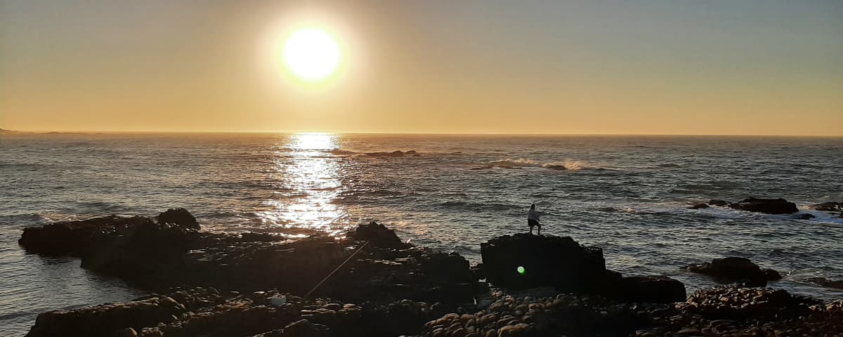 Fisherman casting at sunset on the Wild Coast at Hole in the Wall