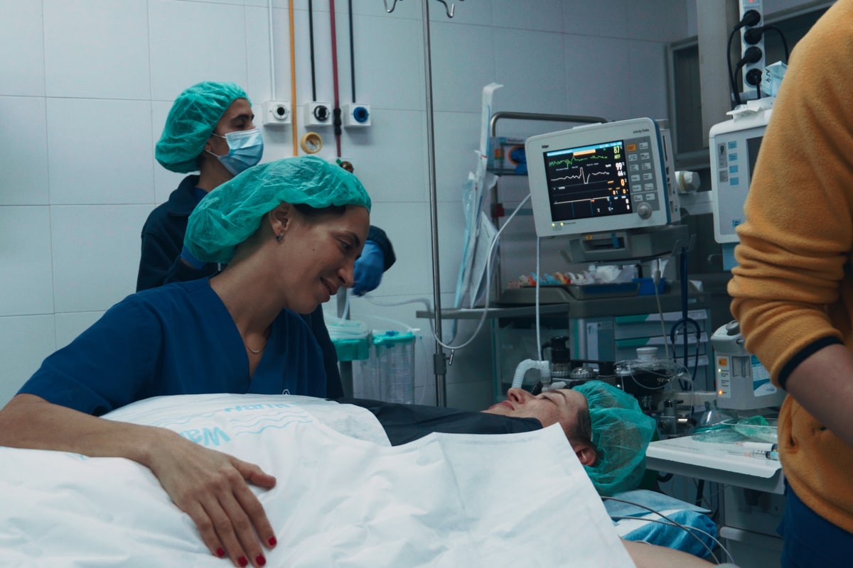Cirurgiã sorridente junto à paciente no bloco operatório