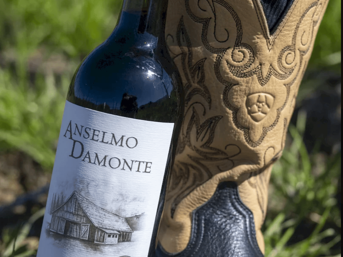 Anselmo Damonte 2023 Cabernet Sauvignon bottle leaning against a cowboy boot in the vineyard, Suisun Valley California