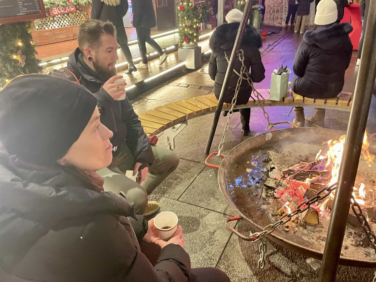 Visitors warming up by a campfire at the Oslo Christmas market