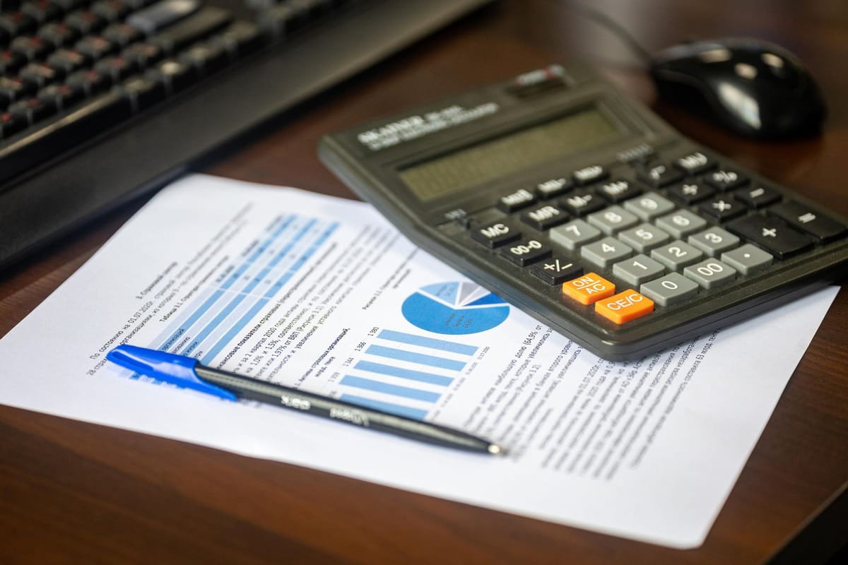 A desk with a calculator, a financial report and a pen