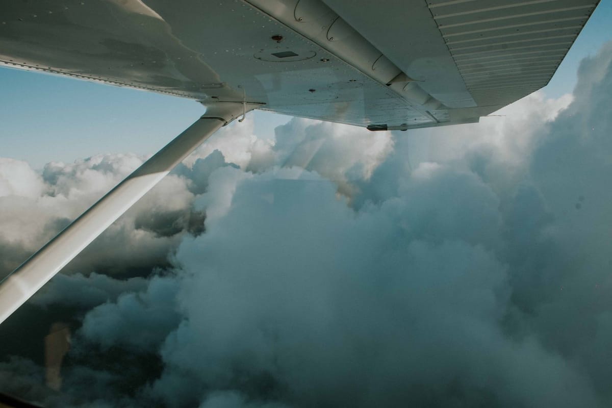 An airplane wing above thick white clouds on a long flight