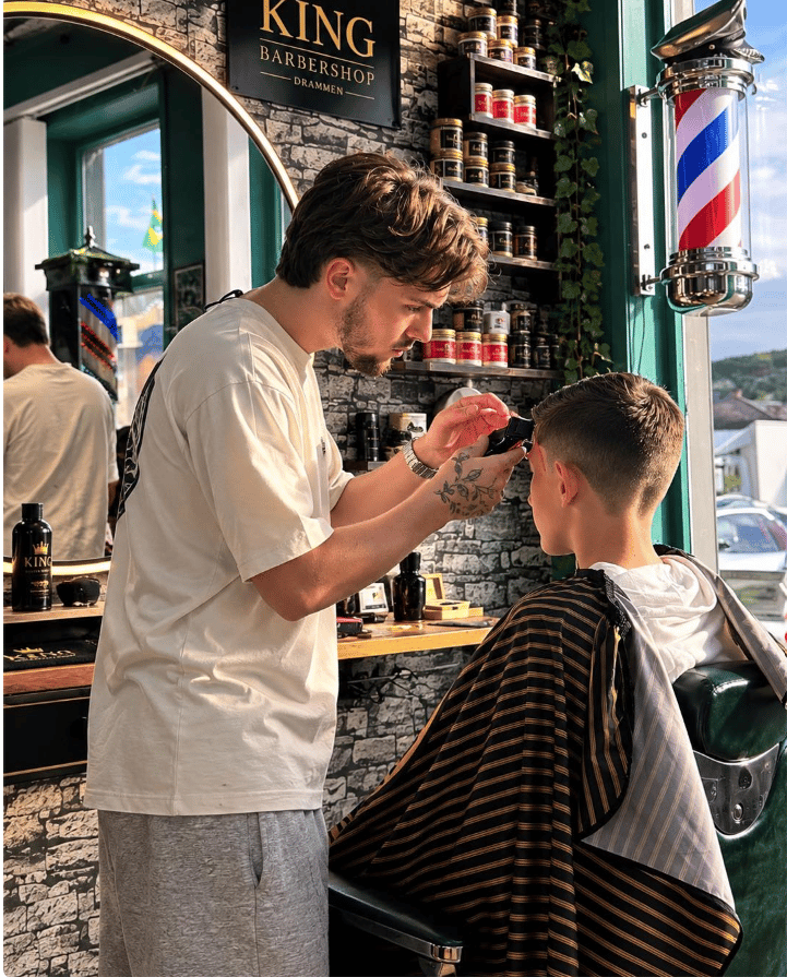 Barber hos King Barbershop former en presis fade med maskin i salongen i Drammen