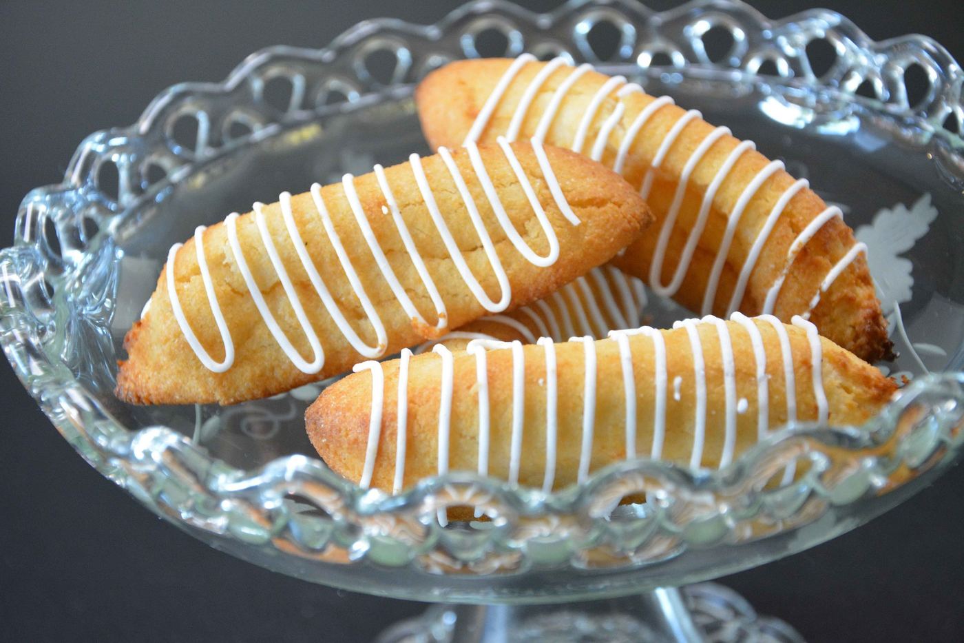 Kransekake almond cake treats drizzled with white icing on a glass stand