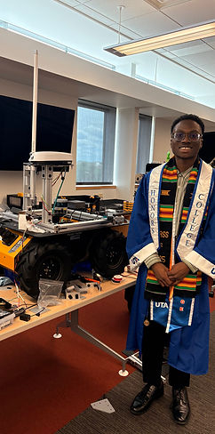 Anthony Aiyedun next to the Husky UGV rover at graduation