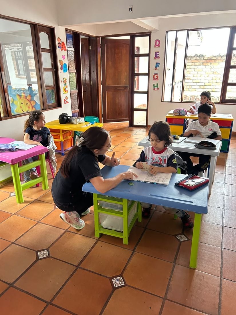 Profesora explicando una tarea a un niño en su mesa