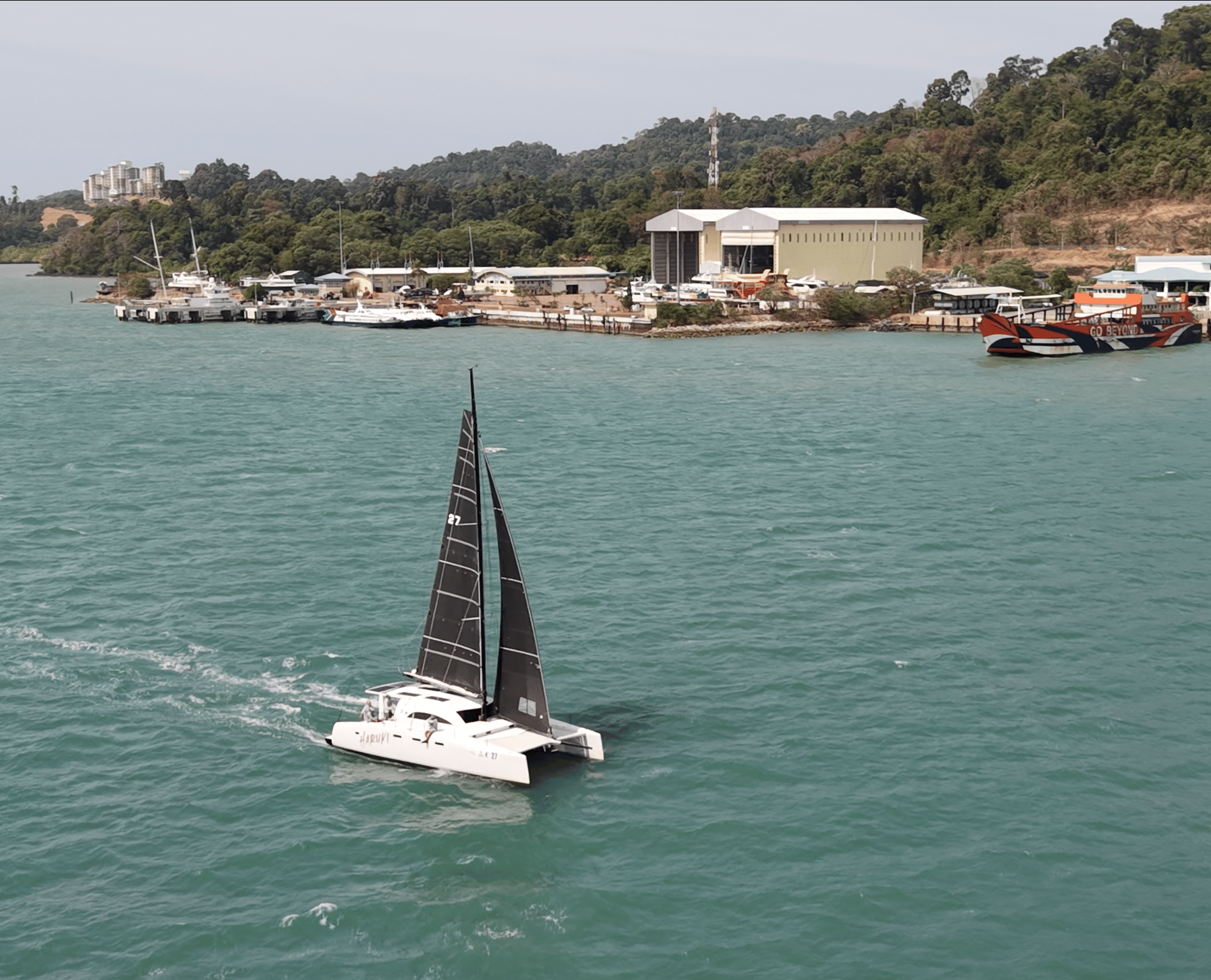 A catamaran sailing past Lunas Shipyard on Langkawi