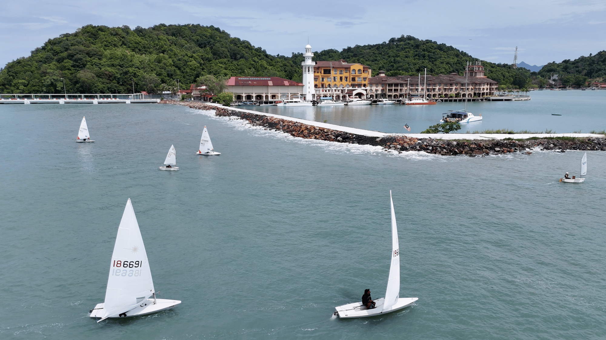 Resorts World Langkawi marina with its lighthouse, seen from the water as dinghies sail past