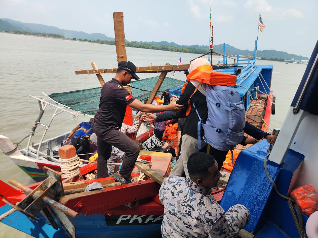 Marine Police personnel helping passengers in life jackets from the grounded ferry onto a fishing boat