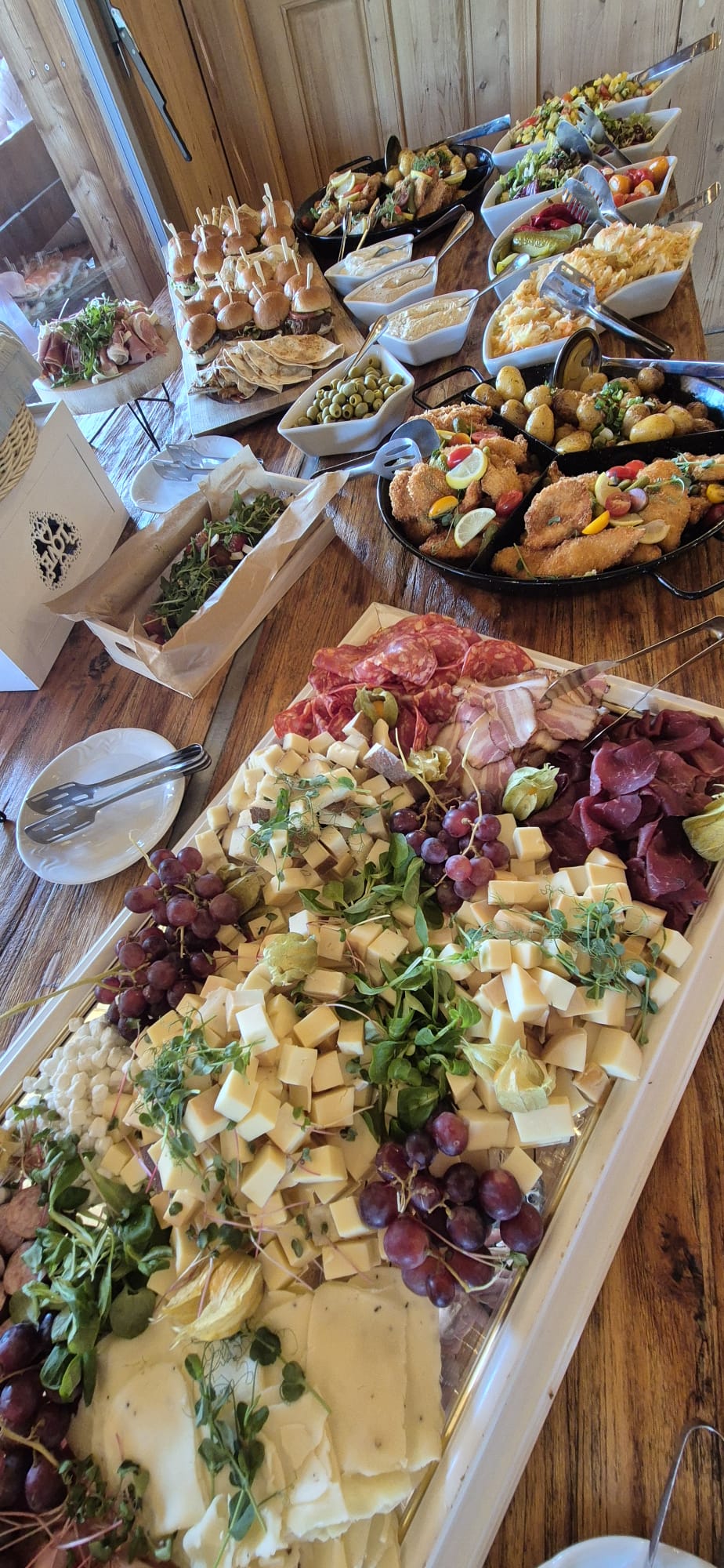 Sýrová tabule s charcuterií, hrozny a saláty na svatební recepci