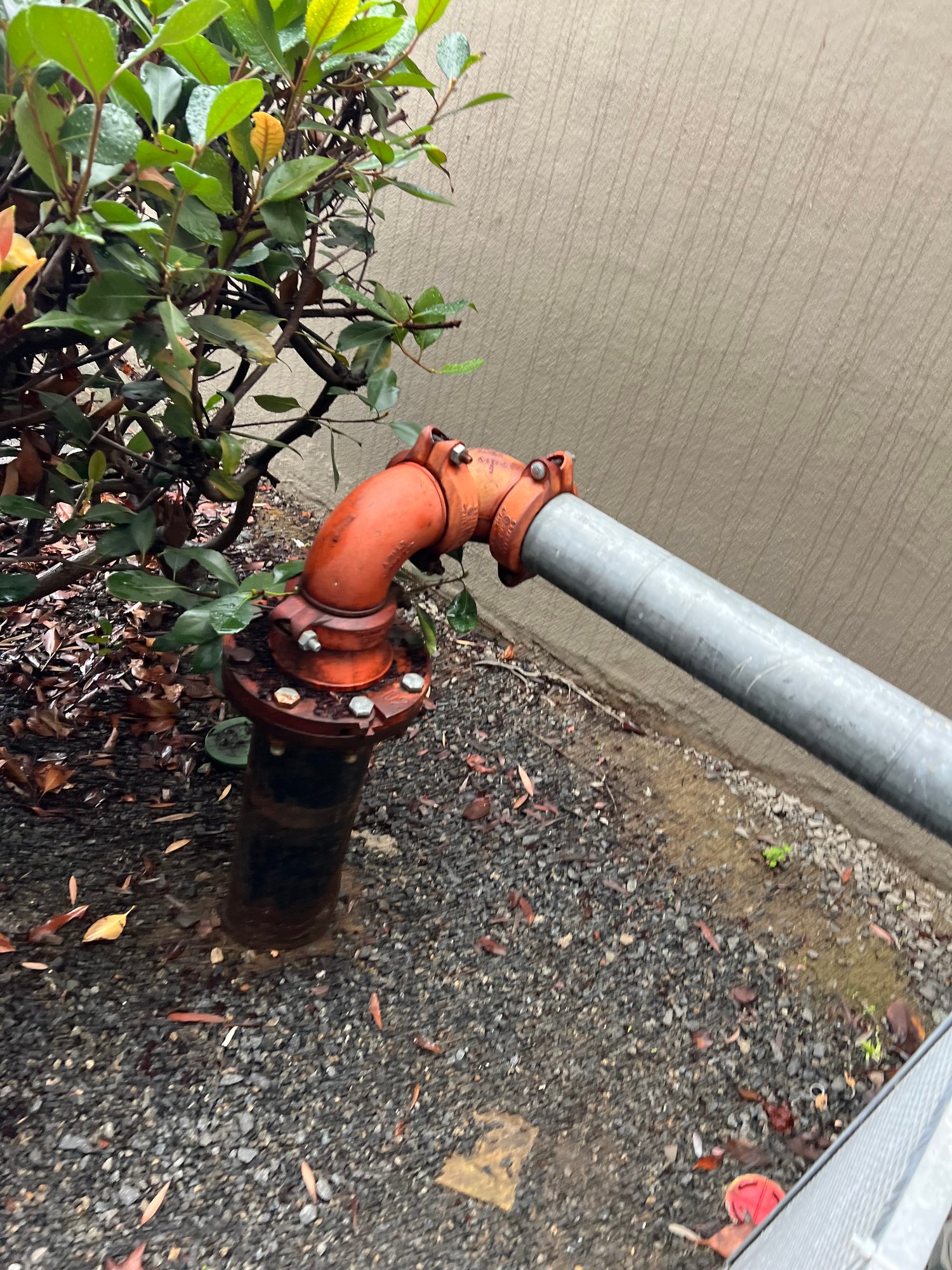 Newly installed orange backflow assembly with galvanized pipe connection