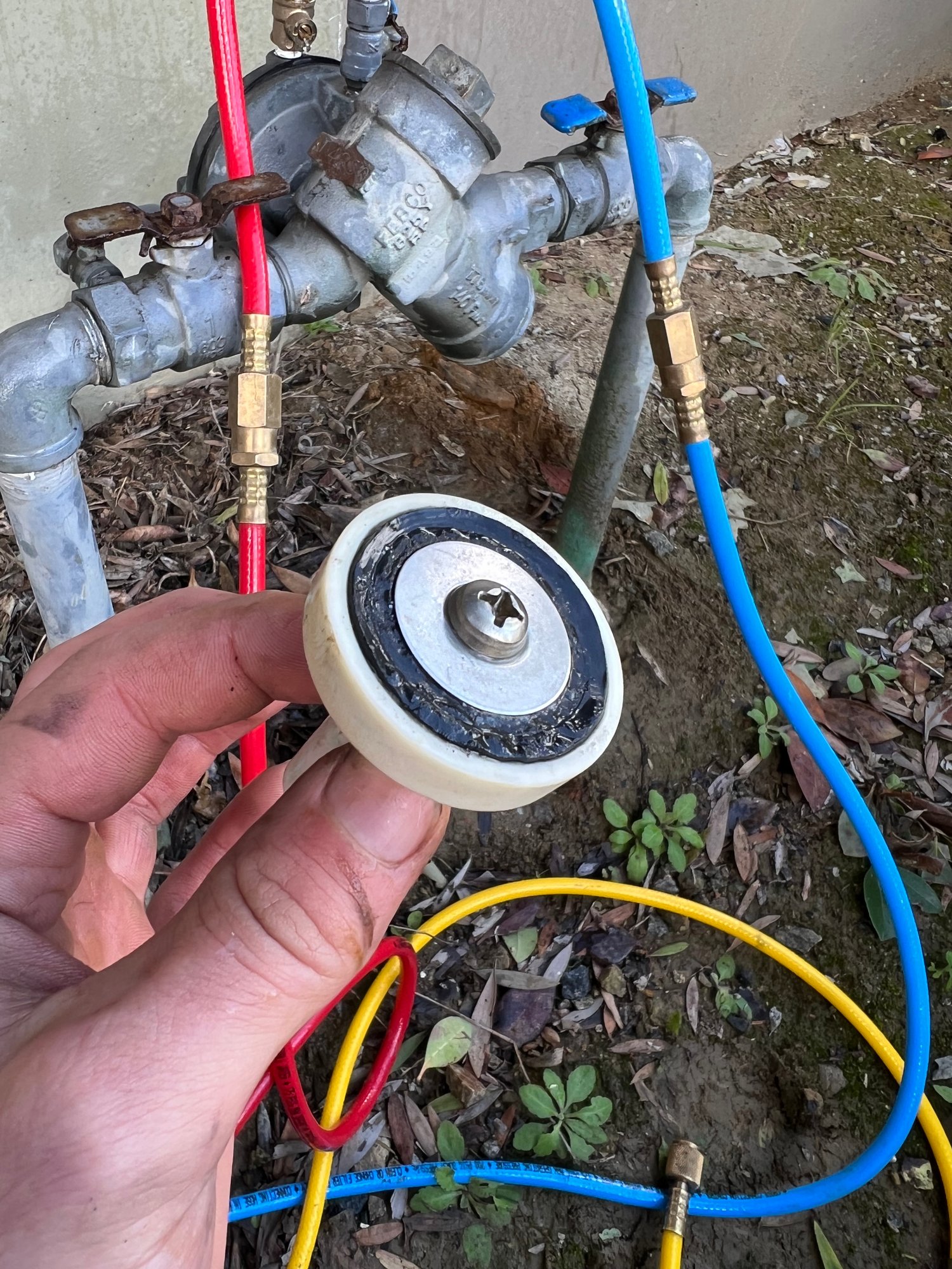 Technician holding removed check valve disc during backflow repair