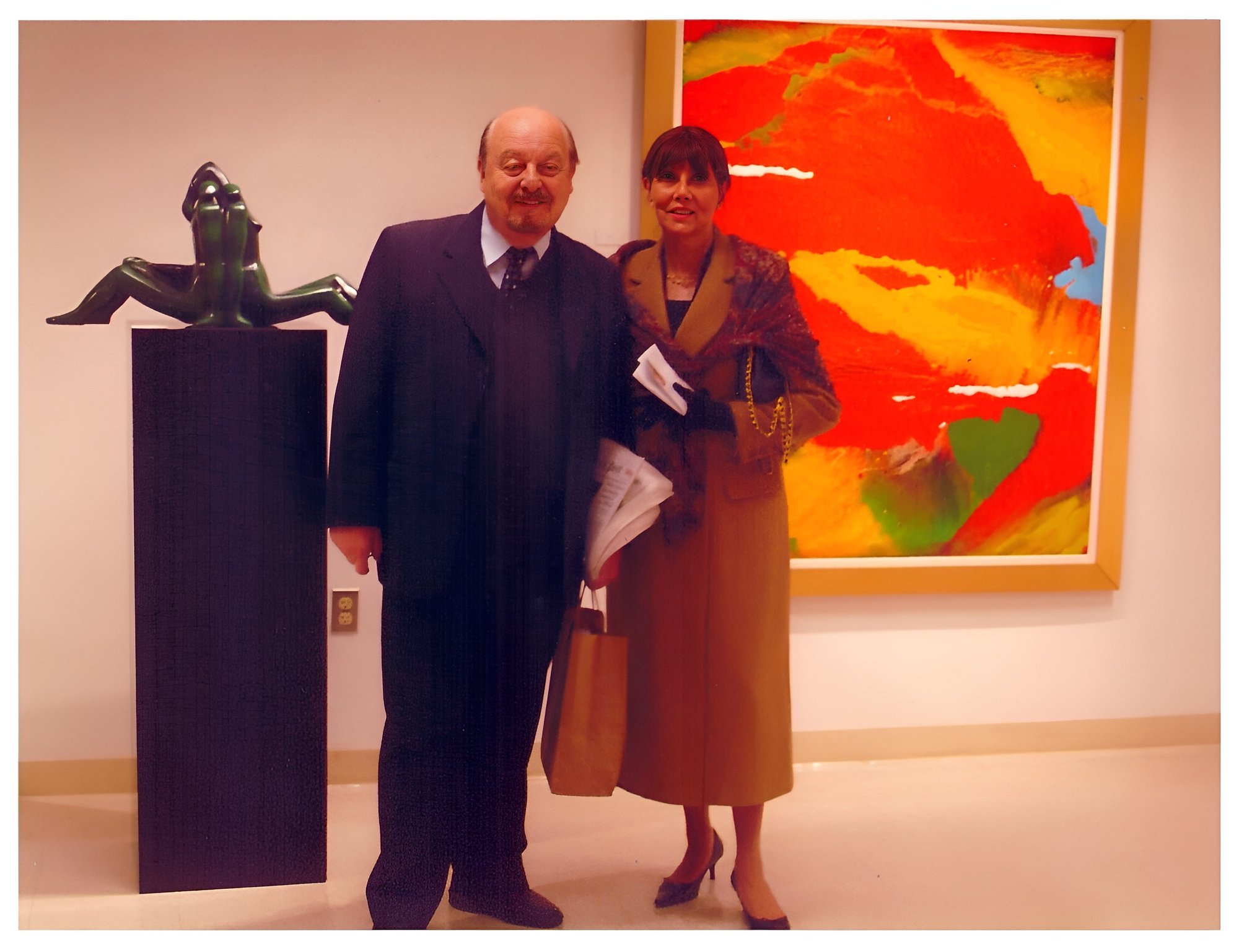 Margarita em abertura de exposição com escultura em bronze ao fundo