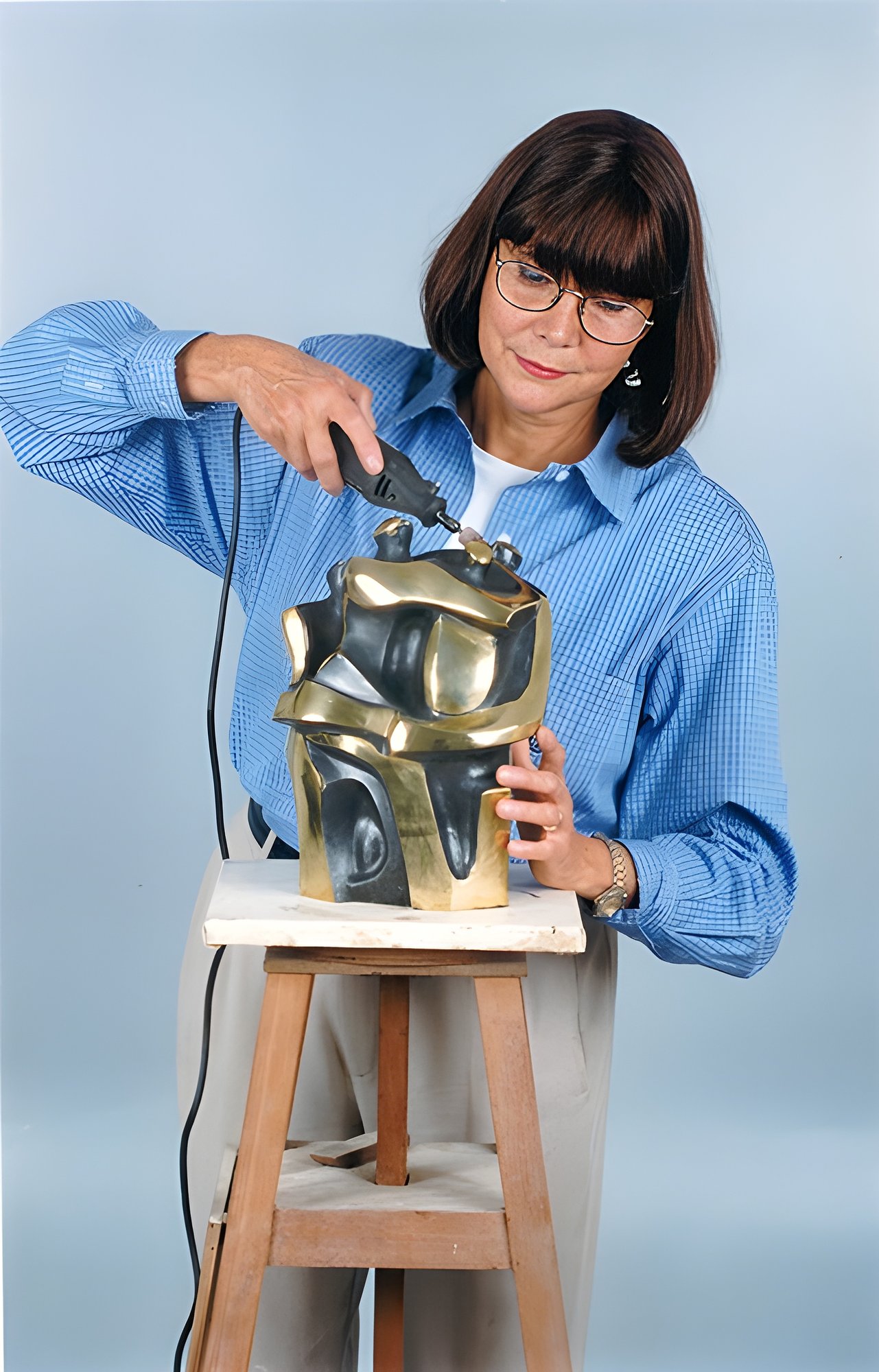 Margarita trabalhando com ferramenta em escultura de bronze