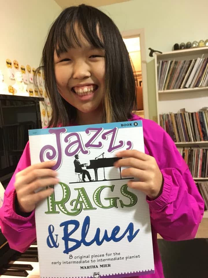 Young student proudly showing her piano book