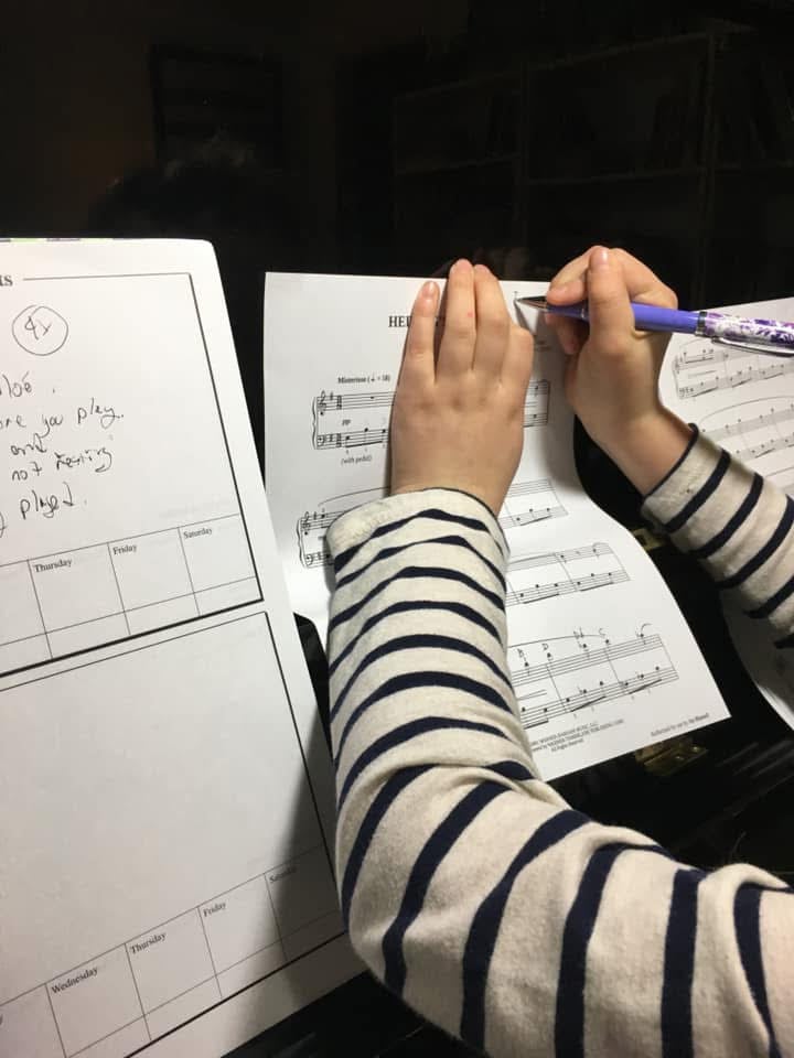 Student annotating piano sheet music at home