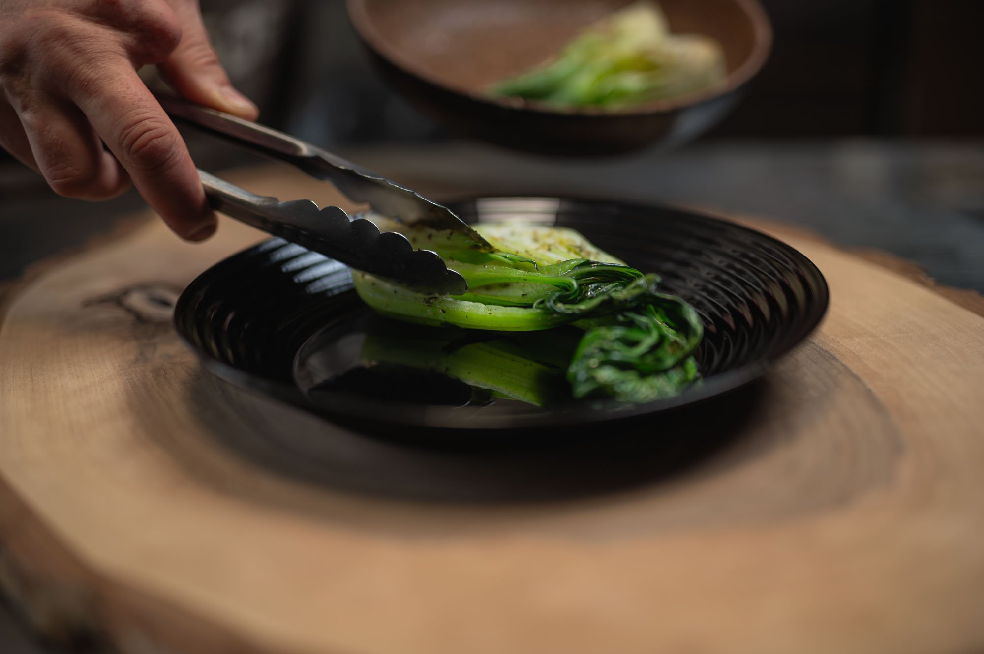 Pak choi kladený na tanier kliešťami