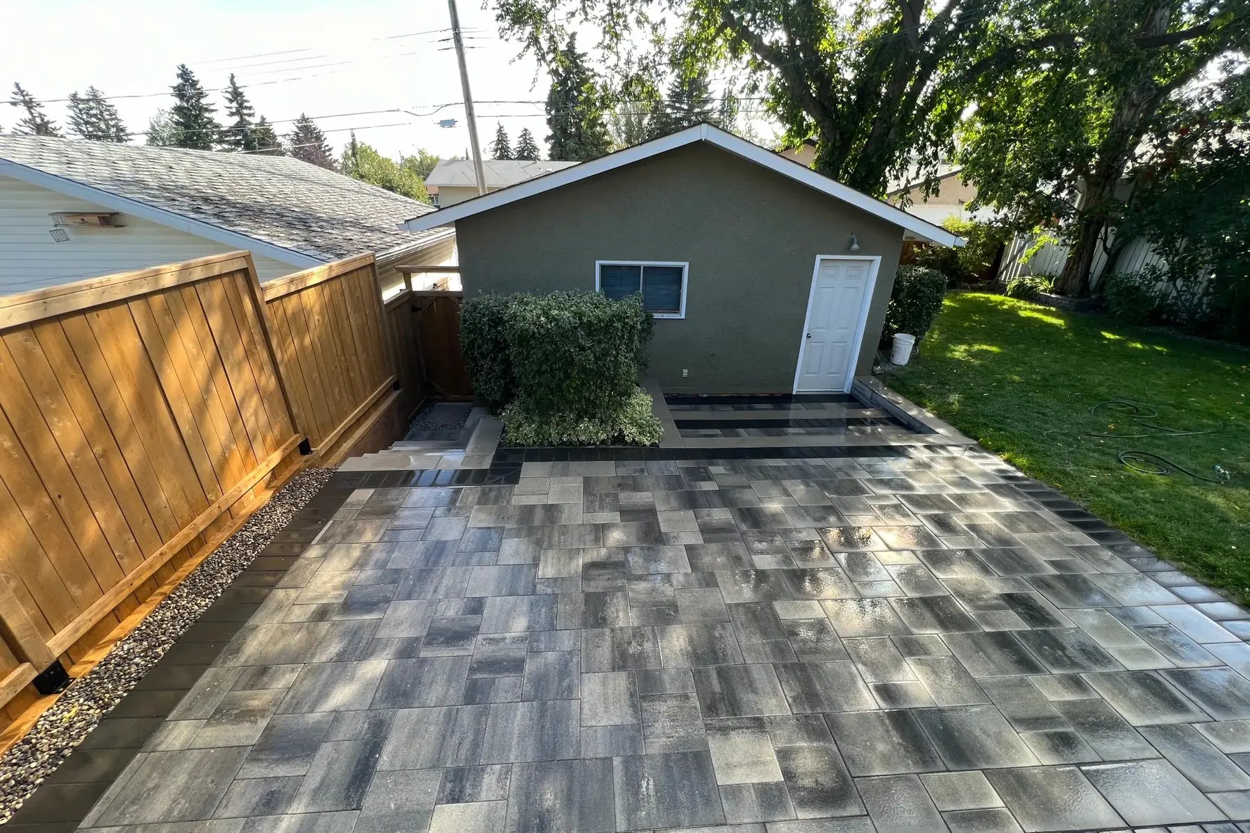 Black paver driveway with cedar fence and garage, Calgary hardscaping
